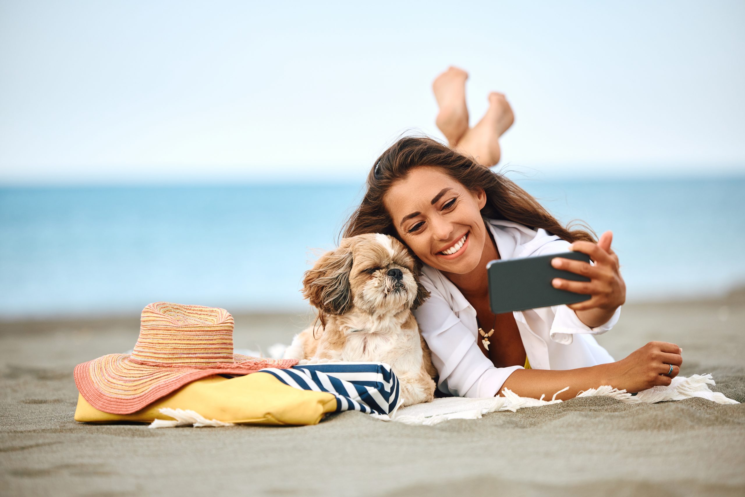 Mulher tirando selfie com cachorro na praia